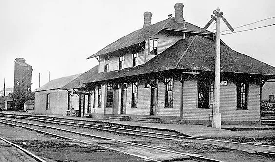 The depot in its early clapboard years beside the tracks