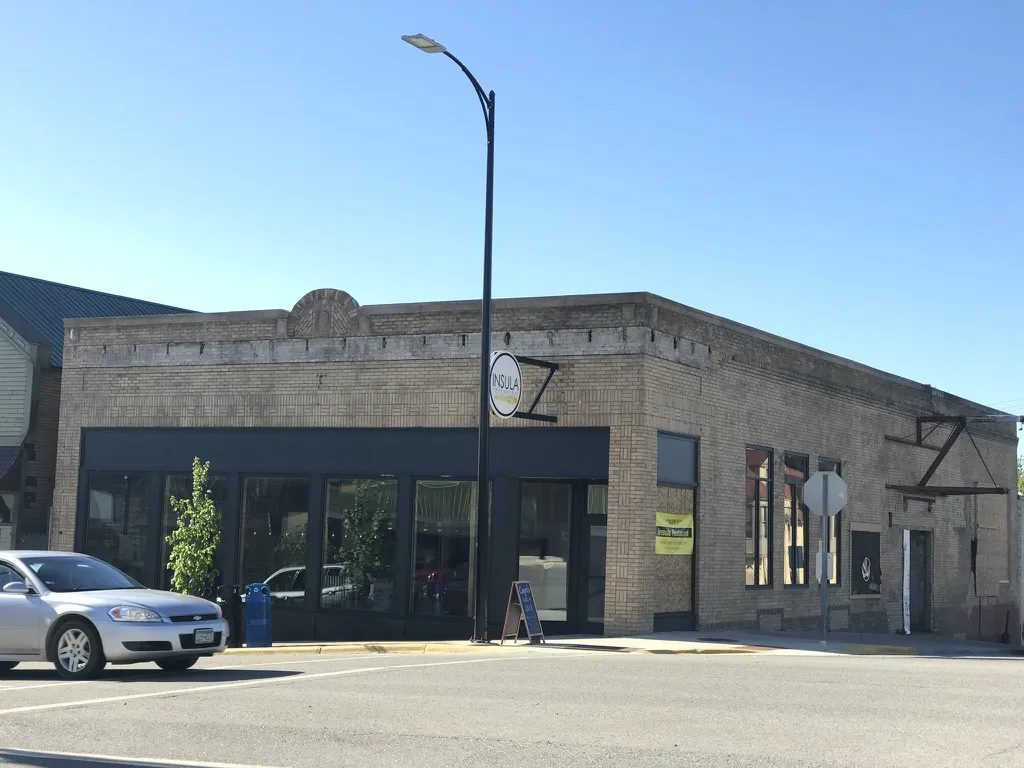 The finished building with a dark storefront and the Insula sign