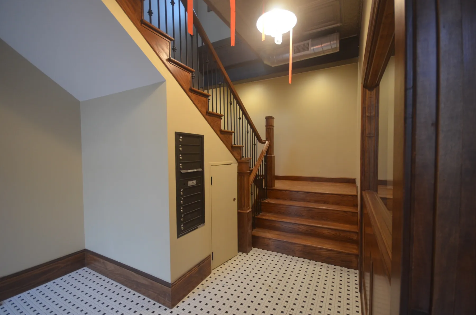 Entry hall with mosaic tile floor, mailboxes and oak stairs