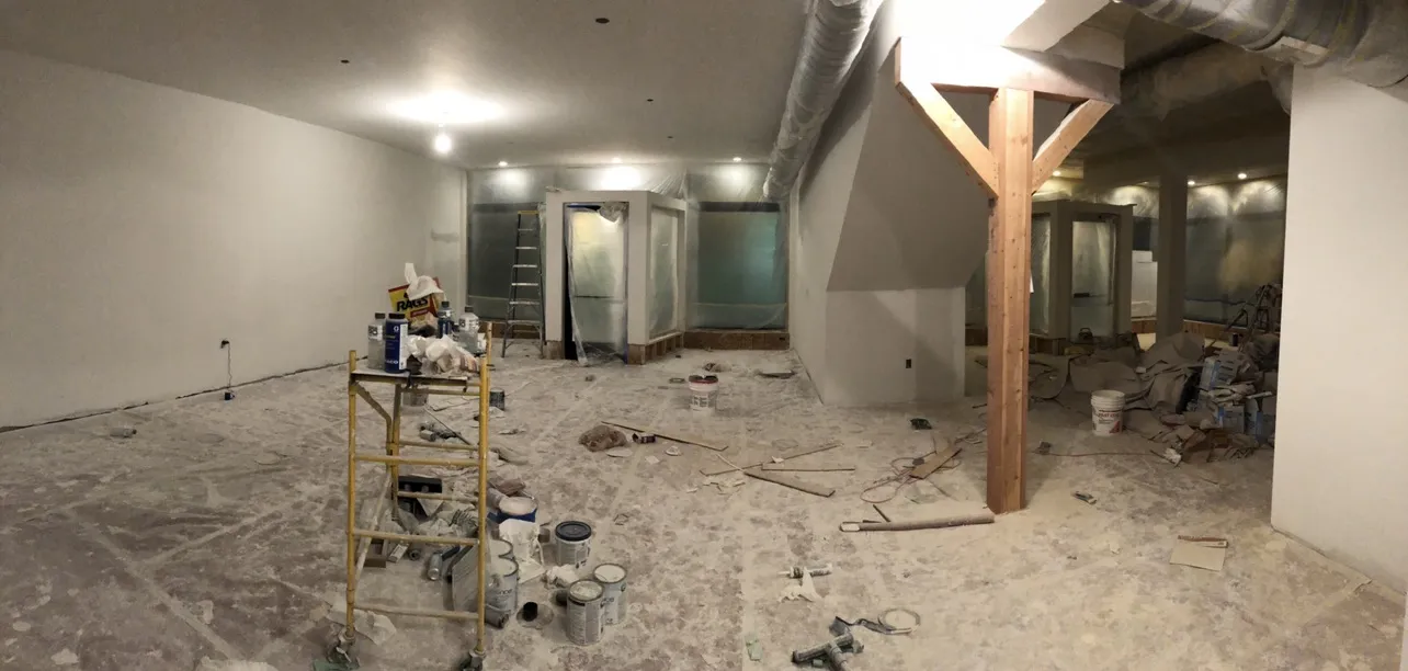 The lower level mid-construction with fresh drywall and paint cans