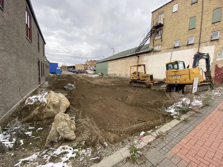 Heavy equipment and large boulders on the graded lot in early winter