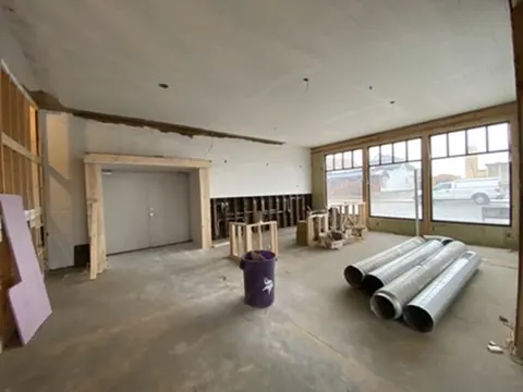 Bright white beadboard walls and ceiling with new storefront windows and ductwork on the floor