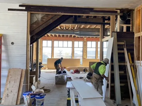 Carpenters working in the open interior beneath the stair opening