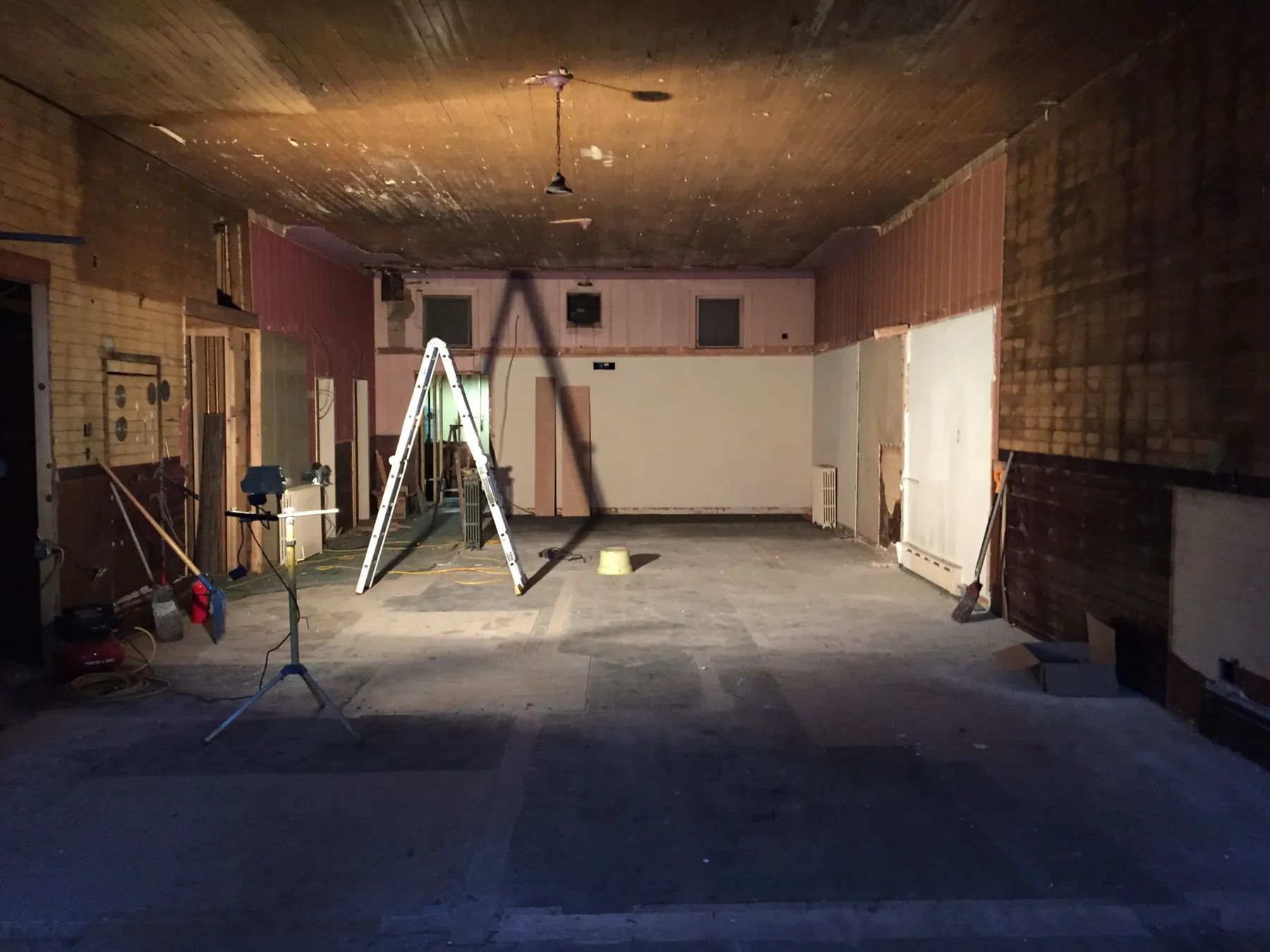 The gutted ground floor with a wood plank ceiling, beadboard walls and a ladder
