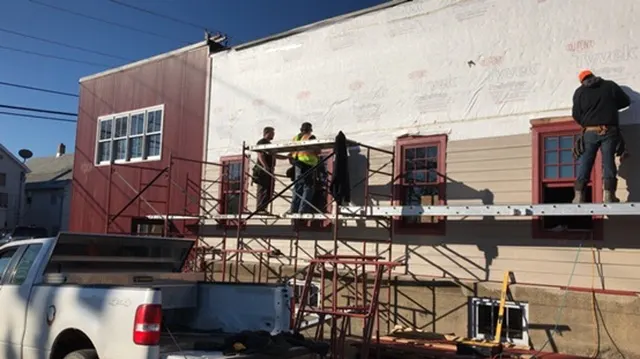Crew on scaffolding siding the side of the building