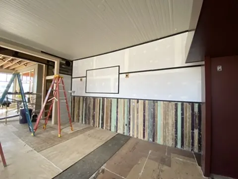 A wall of reclaimed multicolored barnwood below white panels