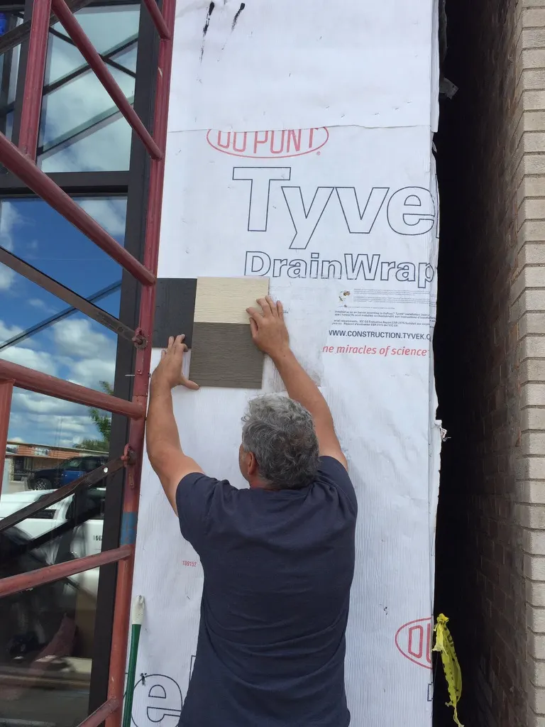 A man holding siding samples against the house wrap