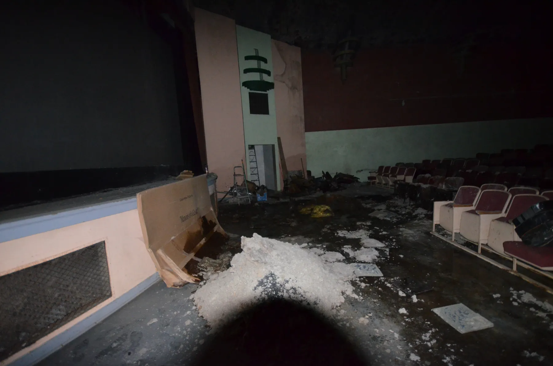 Fallen ceiling material piled on the floor near the stage