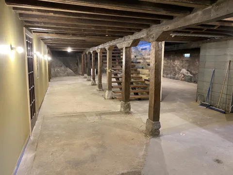 The cleaned-up lower level with timber posts and beams and a wood staircase