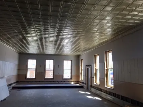 The empty upstairs hall with its tin ceiling revealed