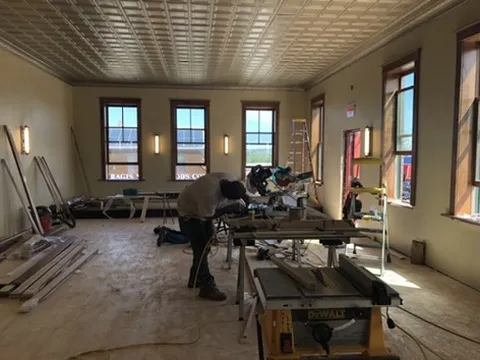A carpenter cutting trim in the upstairs hall